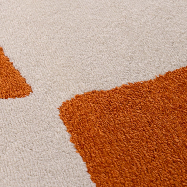 Close-up of a textured rug with orange and beige colors