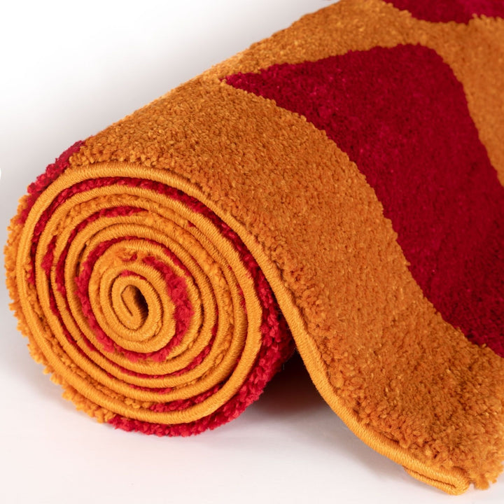 Roll of orange and red patterned fabric on a white background