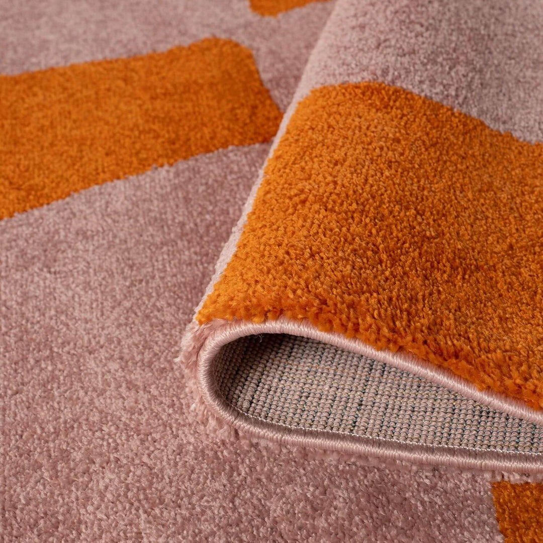 Close-up of a textured rug with orange and pink geometric pattern