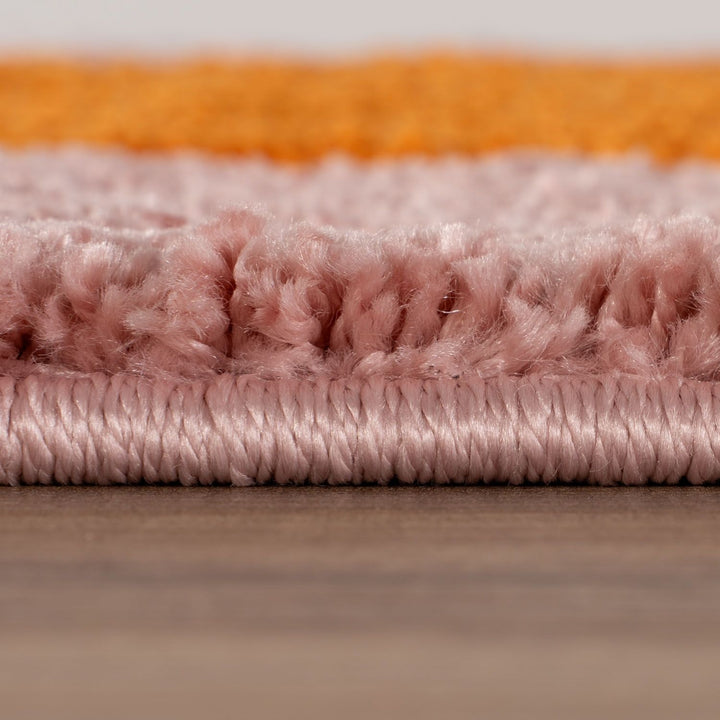 Close-up of pink and orange textured fabric samples on a wooden surface.