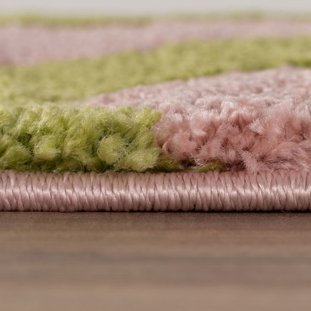 Close-up of a pink and green striped rug on a wooden floor.