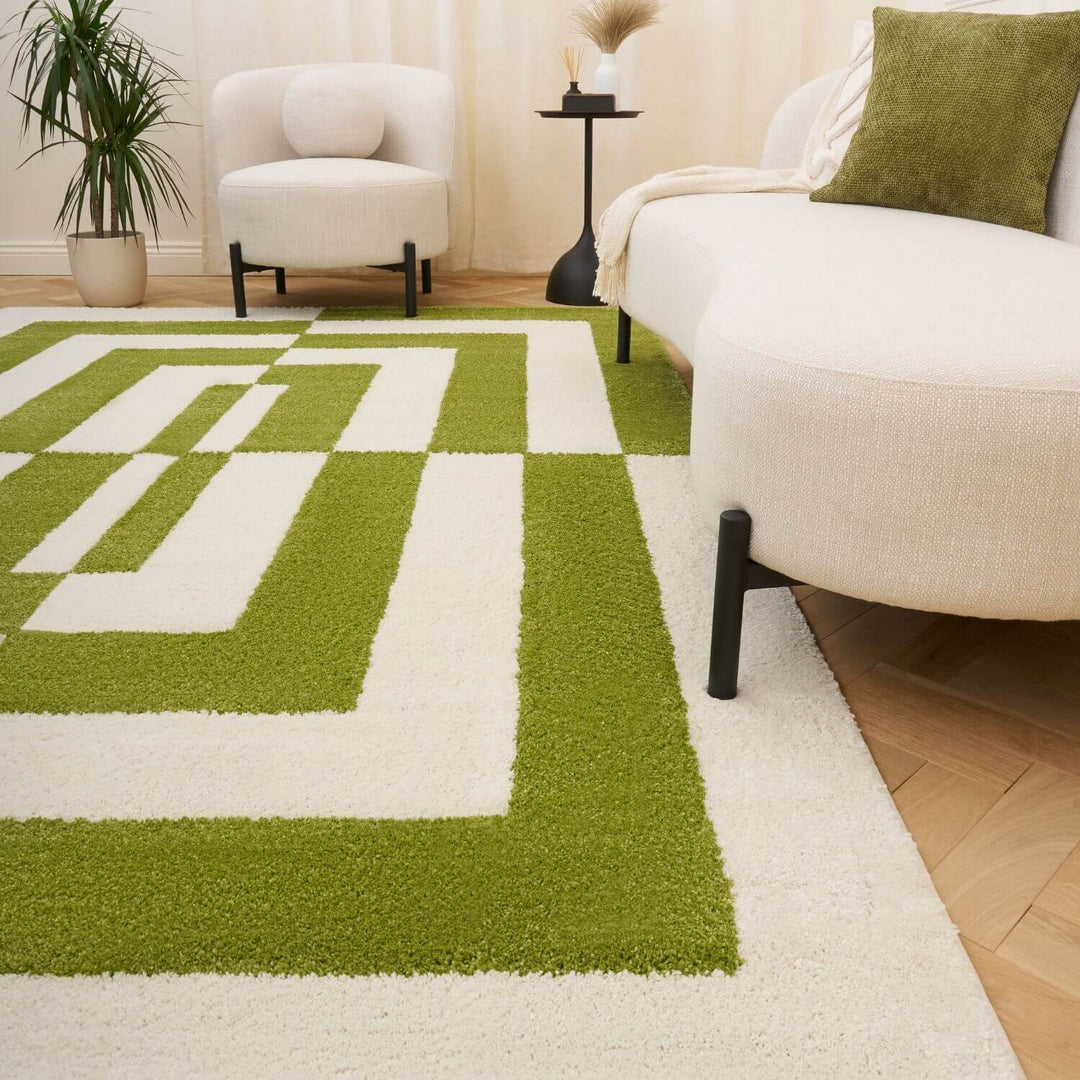 Green and white geometric patterned rug in a living room setting with a couch and chair.