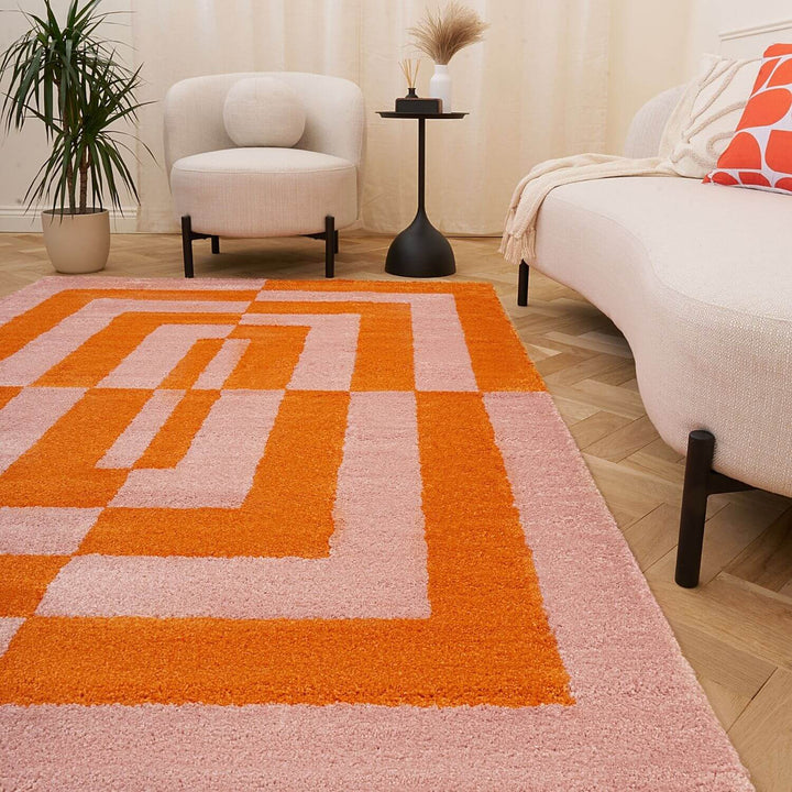 Living room with a geometric patterned rug, white armchair, and beige sofa.