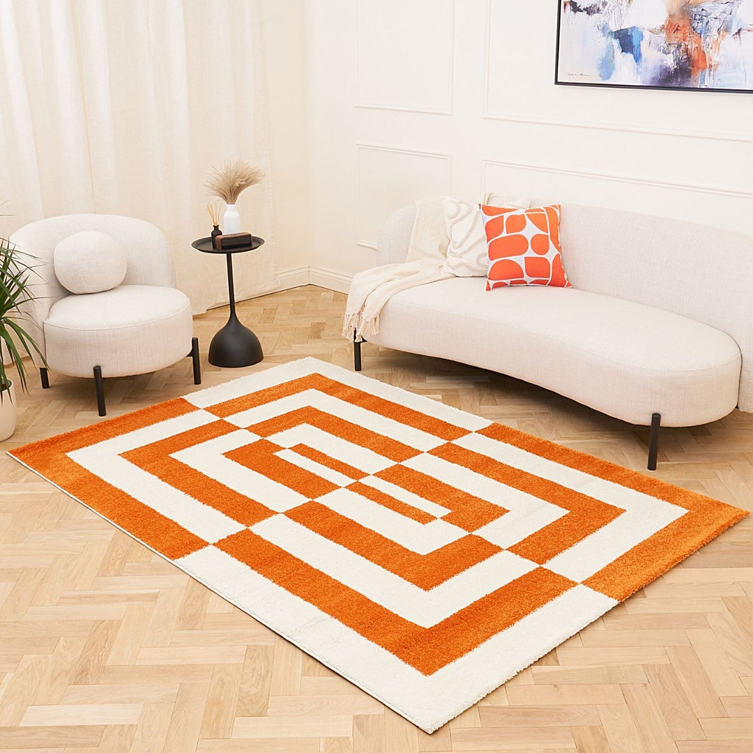 Orange and white geometric rug on a wooden floor with a white sofa and chair in the background.