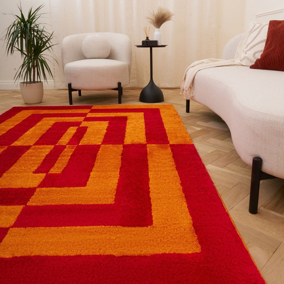 Living room with a red and orange checkered rug, white armchair, and beige sofa.