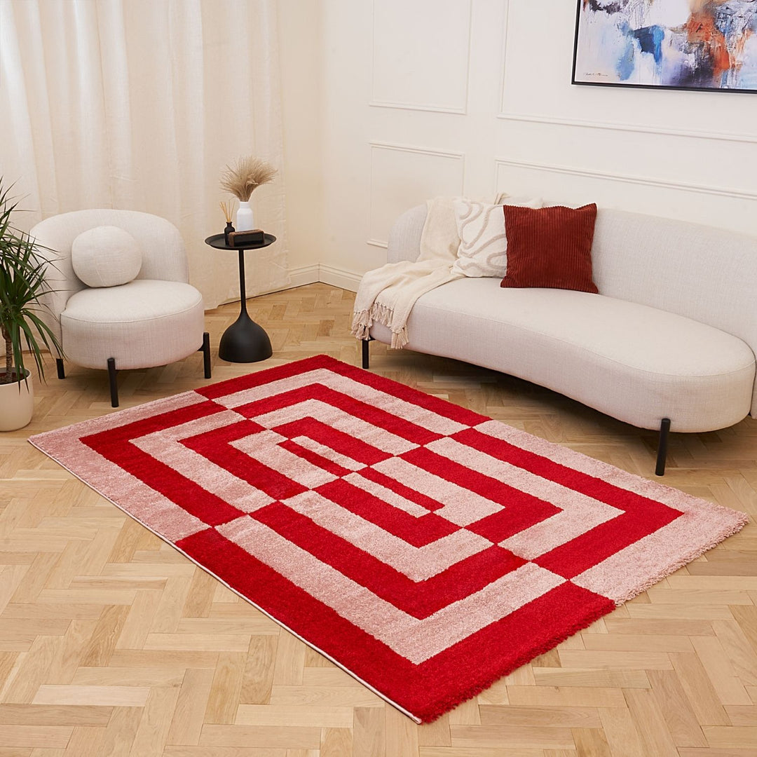 Red and white geometric rug in a living room with a sofa and chair.