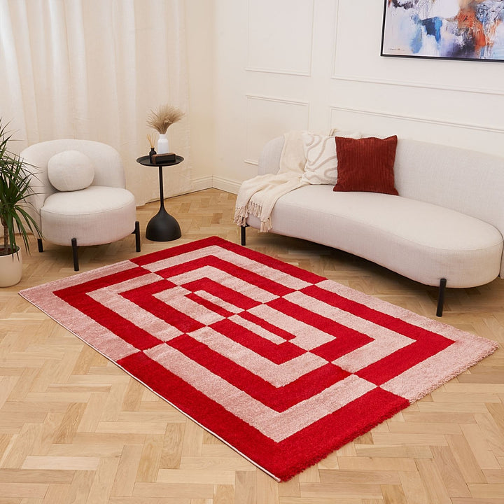 Red and white geometric rug in a living room with a sofa and chair.
