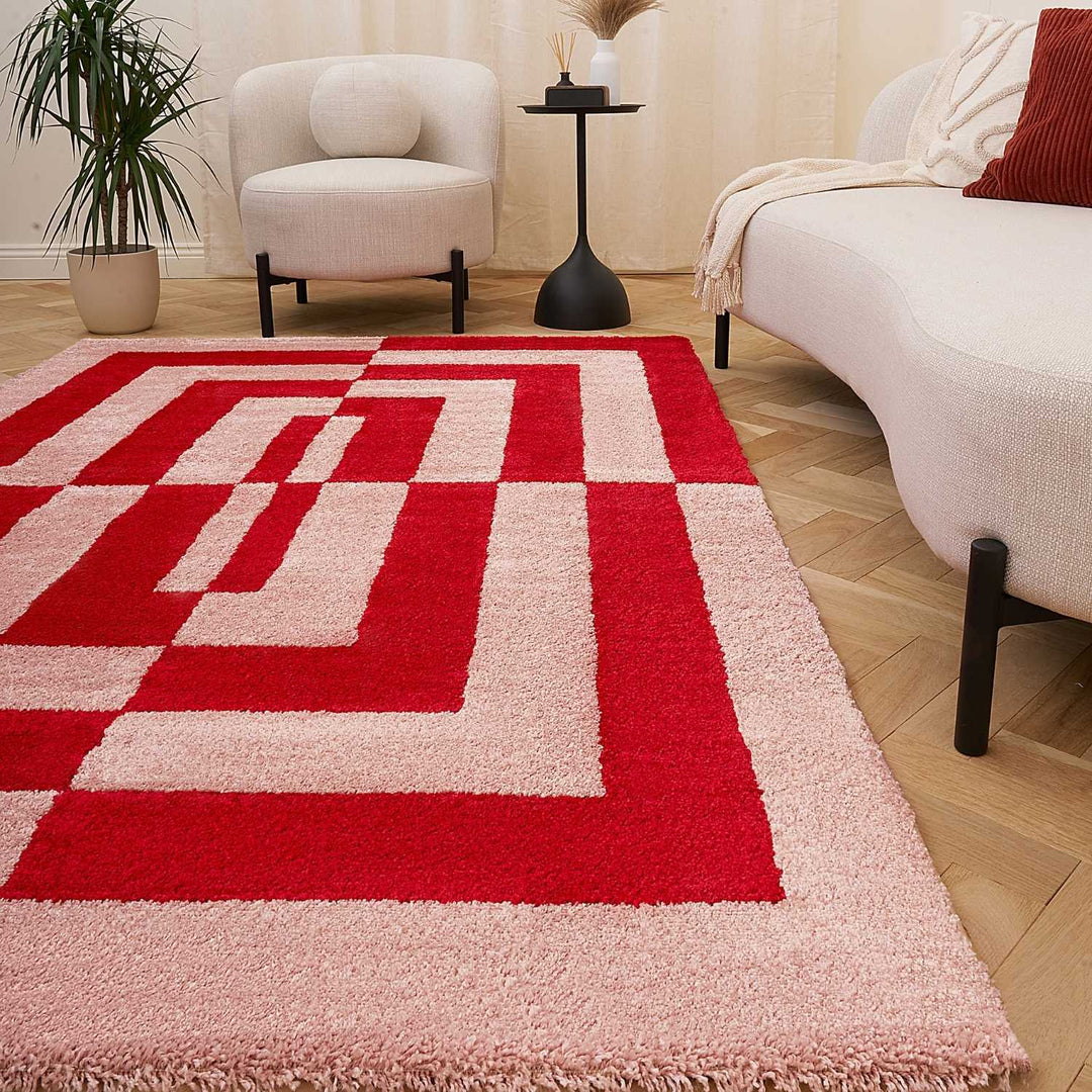 Red and beige geometric patterned rug in a living room setting with furniture and decor.