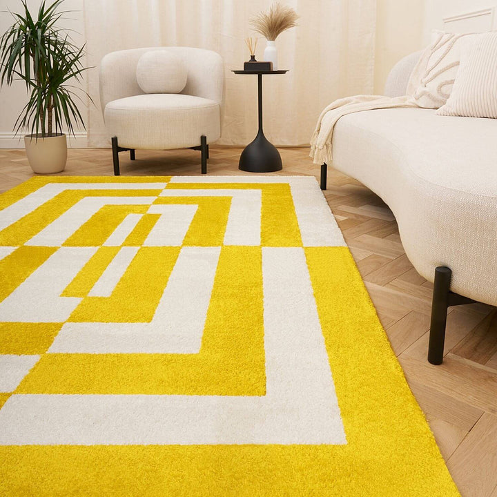 Yellow and white geometric patterned rug in a living room setting with a sofa and chair.