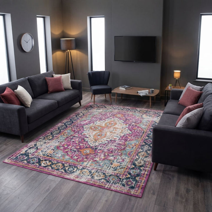 Living room with dark gray sofas, a colorful patterned rug, and a television on the wall.