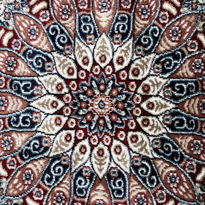 Close-up of a patterned rug with intricate designs in red, beige, and black.