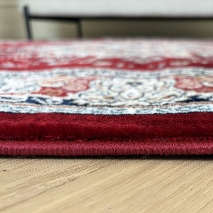 Close-up of a red and patterned rug on a wooden floor.