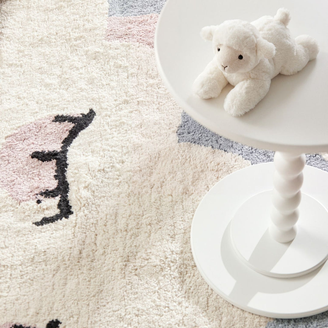White teddy bear on a white stool next to a textured rug with abstract patterns