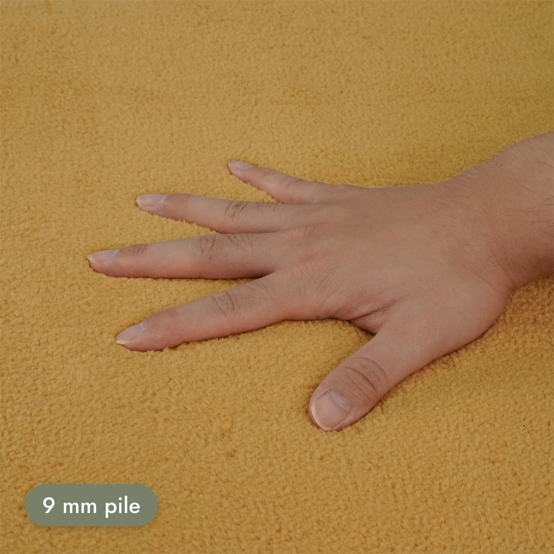 Washmellow ochre washable rug, close-up of the soft 9mm pile under a hand | The Rugs