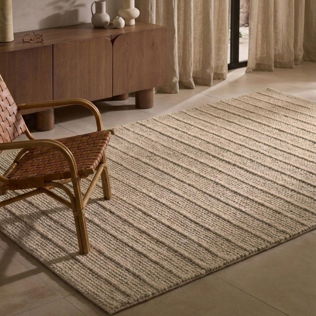 Woven rug on a tiled floor with a wooden chair and sideboard in the background.