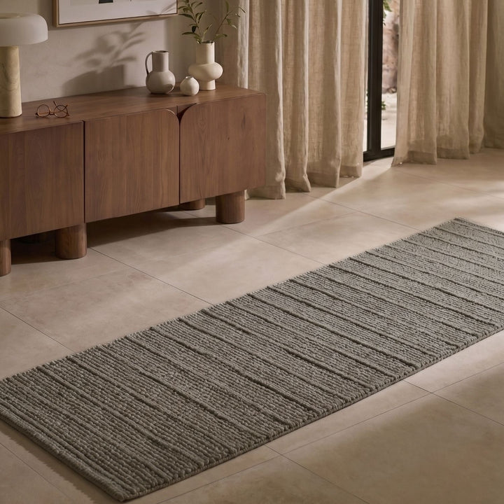 Gray runner rug on a tiled floor in a room with wooden furniture and curtains.