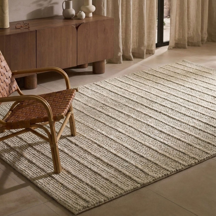 Beige rug on a tiled floor with a wooden chair and sideboard in the background.