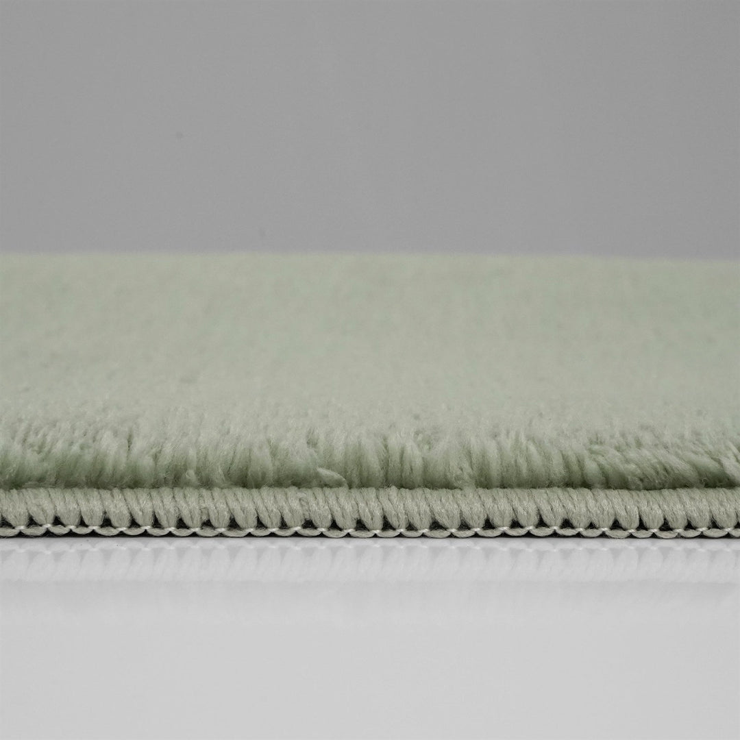 Washmellow sage green washable rug, side view of the low pile and edge at floor level | The Rugs