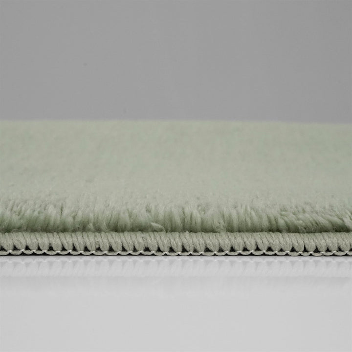 Washmellow sage green washable rug, side view of the low pile and edge at floor level | The Rugs