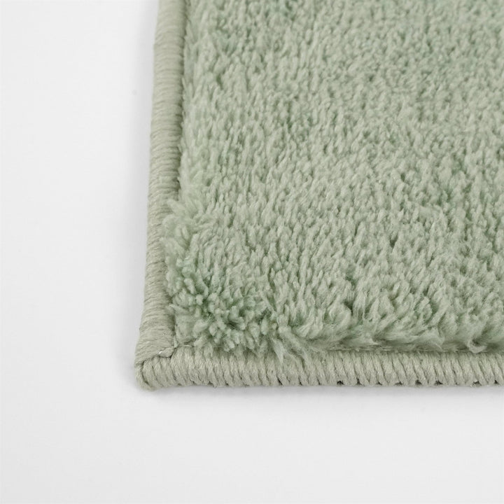 Washmellow sage green washable rug, close-up of the corner and bound edge | The Rugs