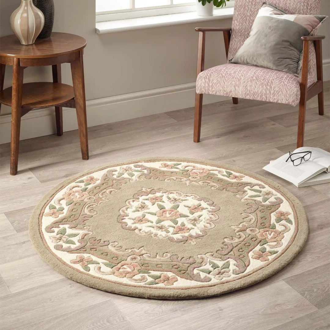 Round decorative rug on a wooden floor with a chair and small table in the background.