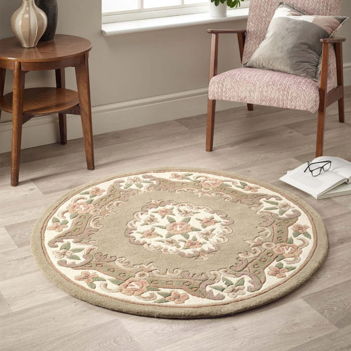Round decorative rug on a wooden floor with a chair and small table in the background.