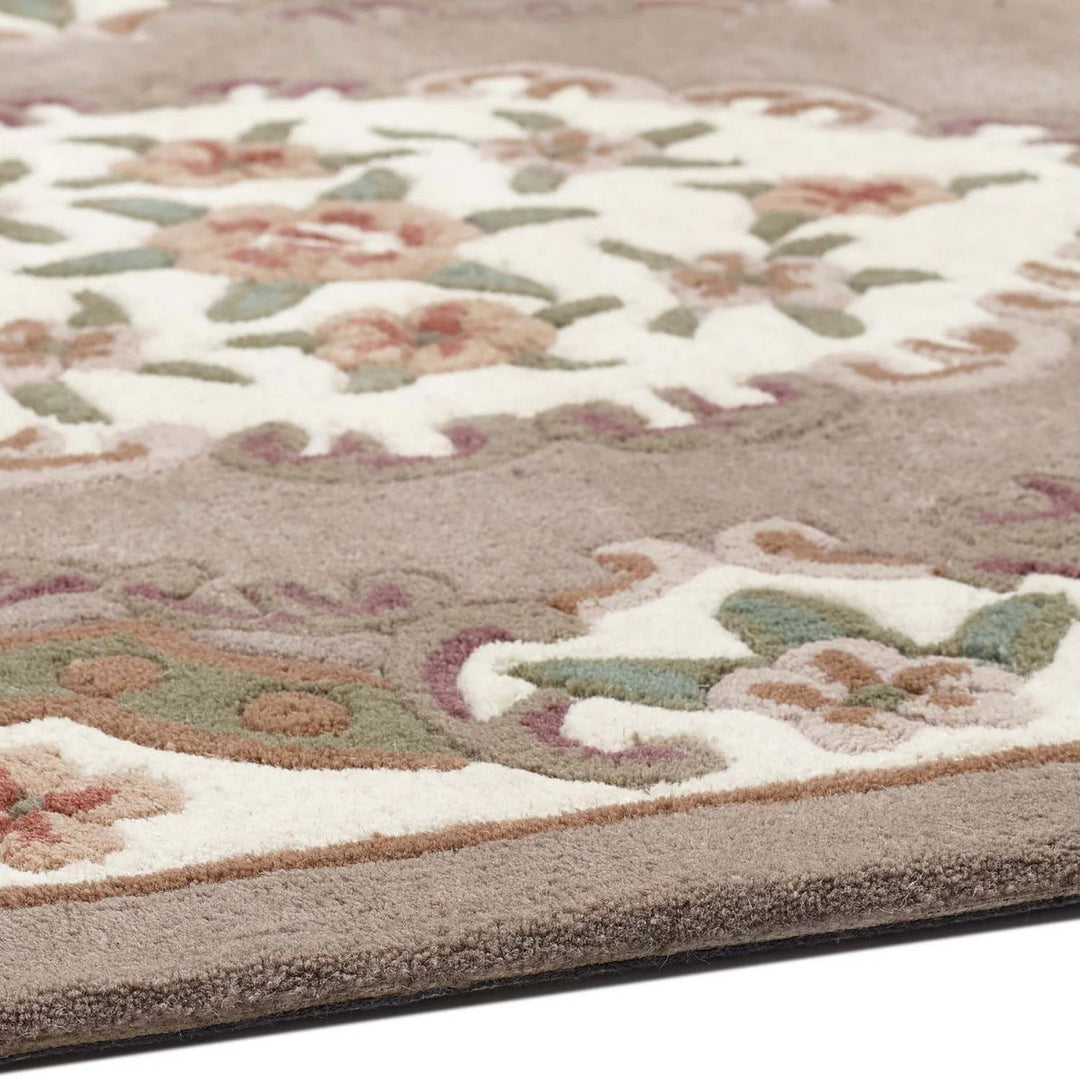 Close-up of a floral patterned rug with beige, green, and brown colors.
