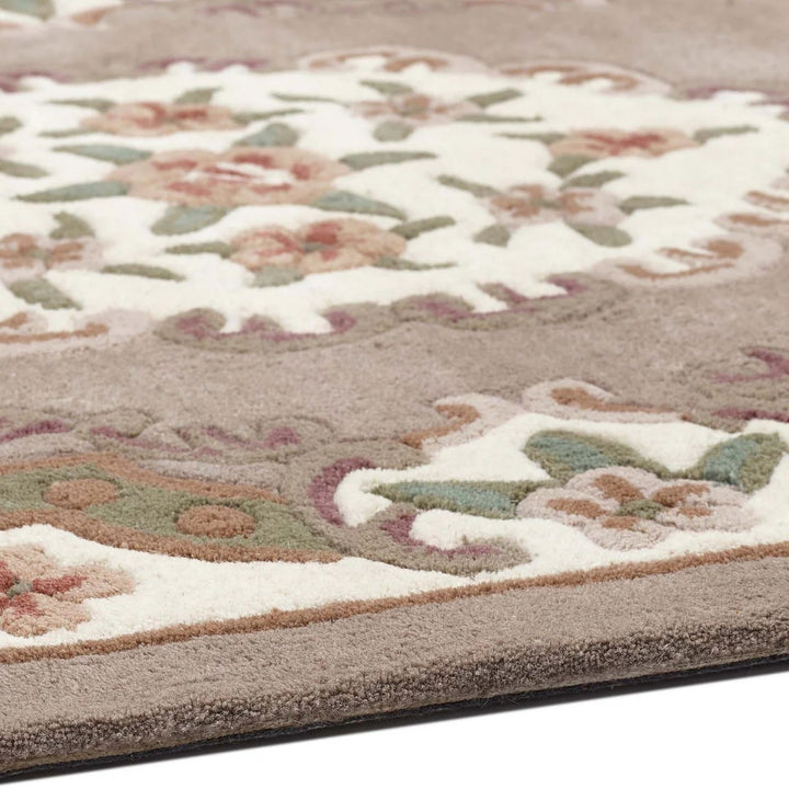 Close-up of a floral patterned rug with beige, green, and brown colors.