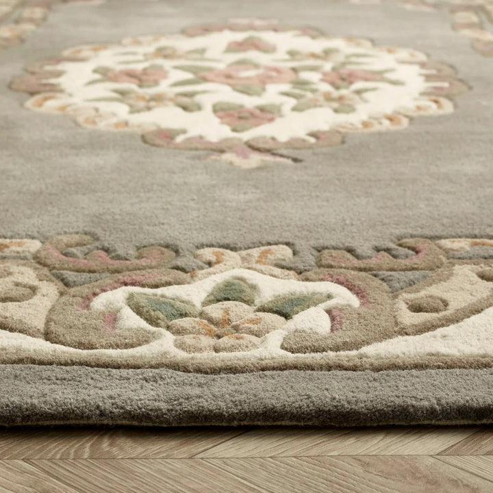 Close-up of a patterned rug with intricate designs on a wooden floor.