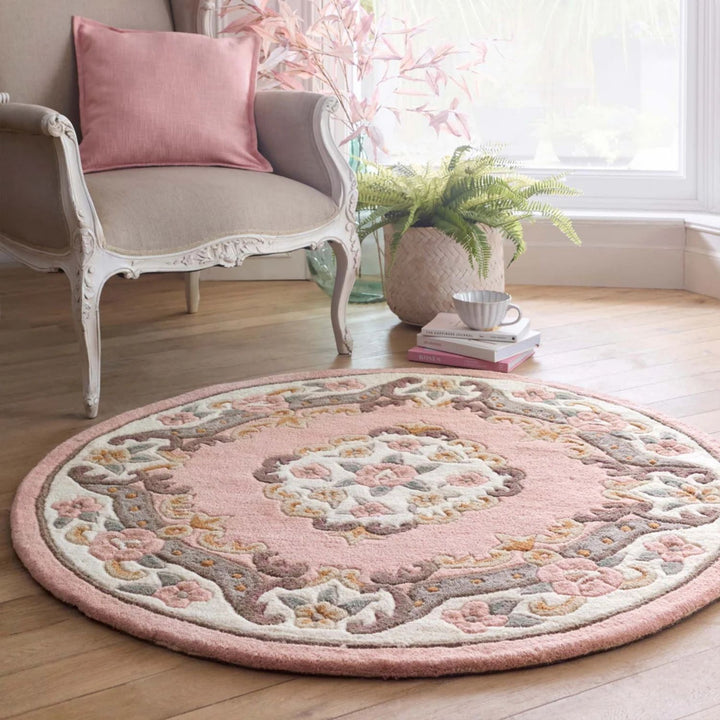 Round pink rug with floral patterns in a room with a chair and decor items.