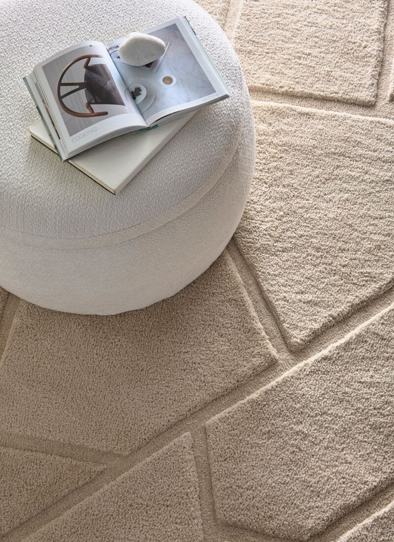 Scandinavian deep pile cream rug beside a fluffy ottoman and an open book, enhancing a cozy interior.