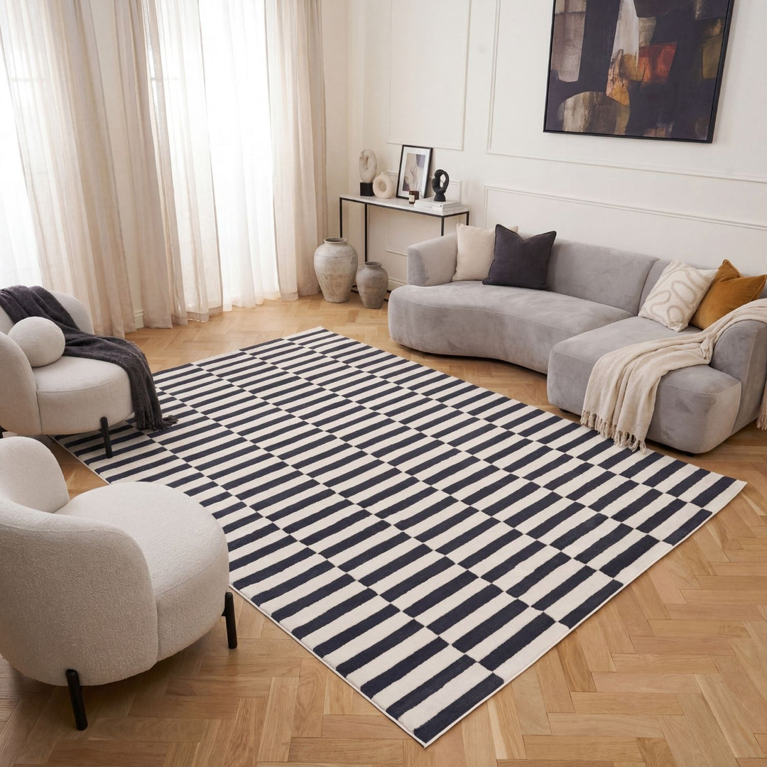 Living room with a striped rug, gray sofa, and white armchair.