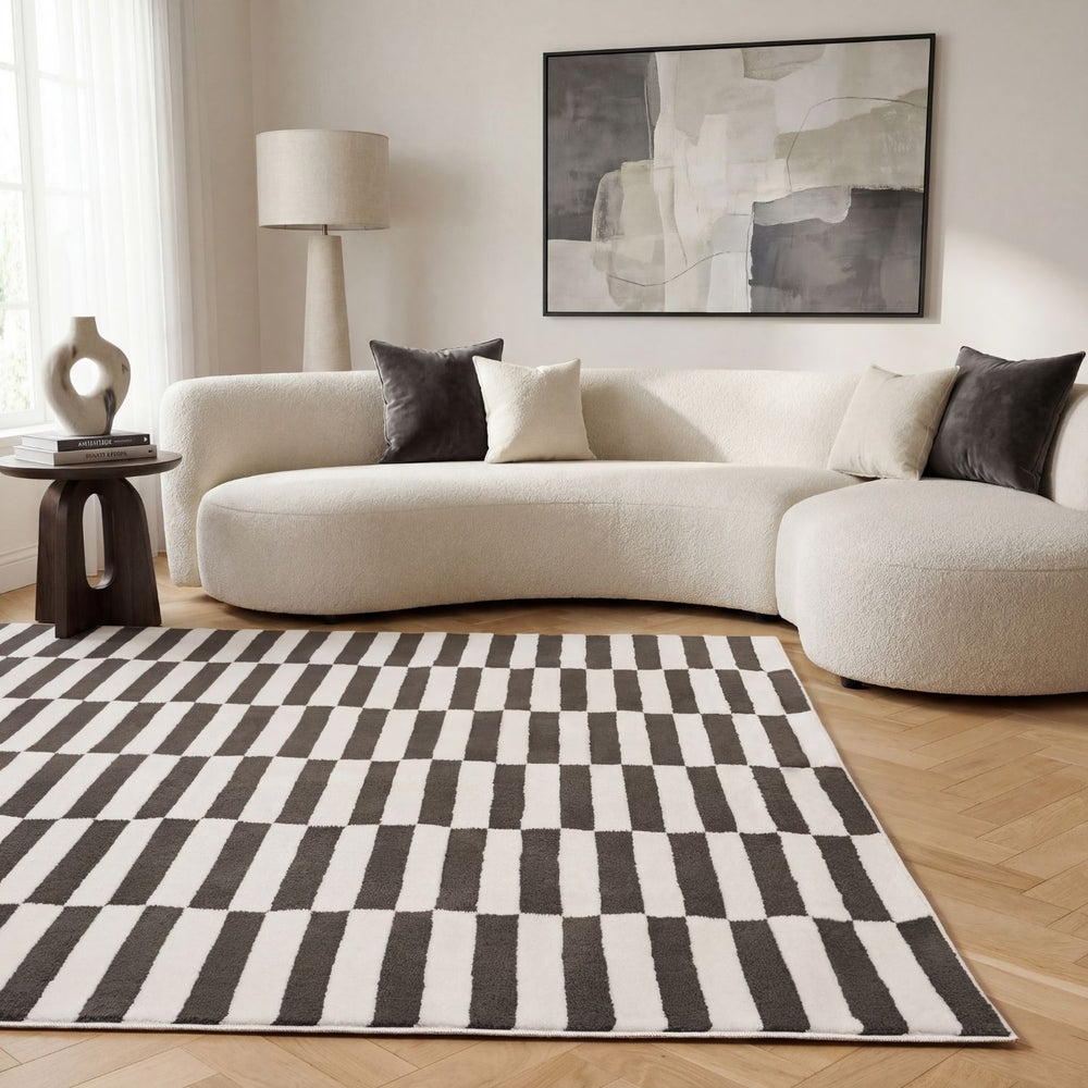 Modern living room with a checkered rug, white sofa, and abstract painting.