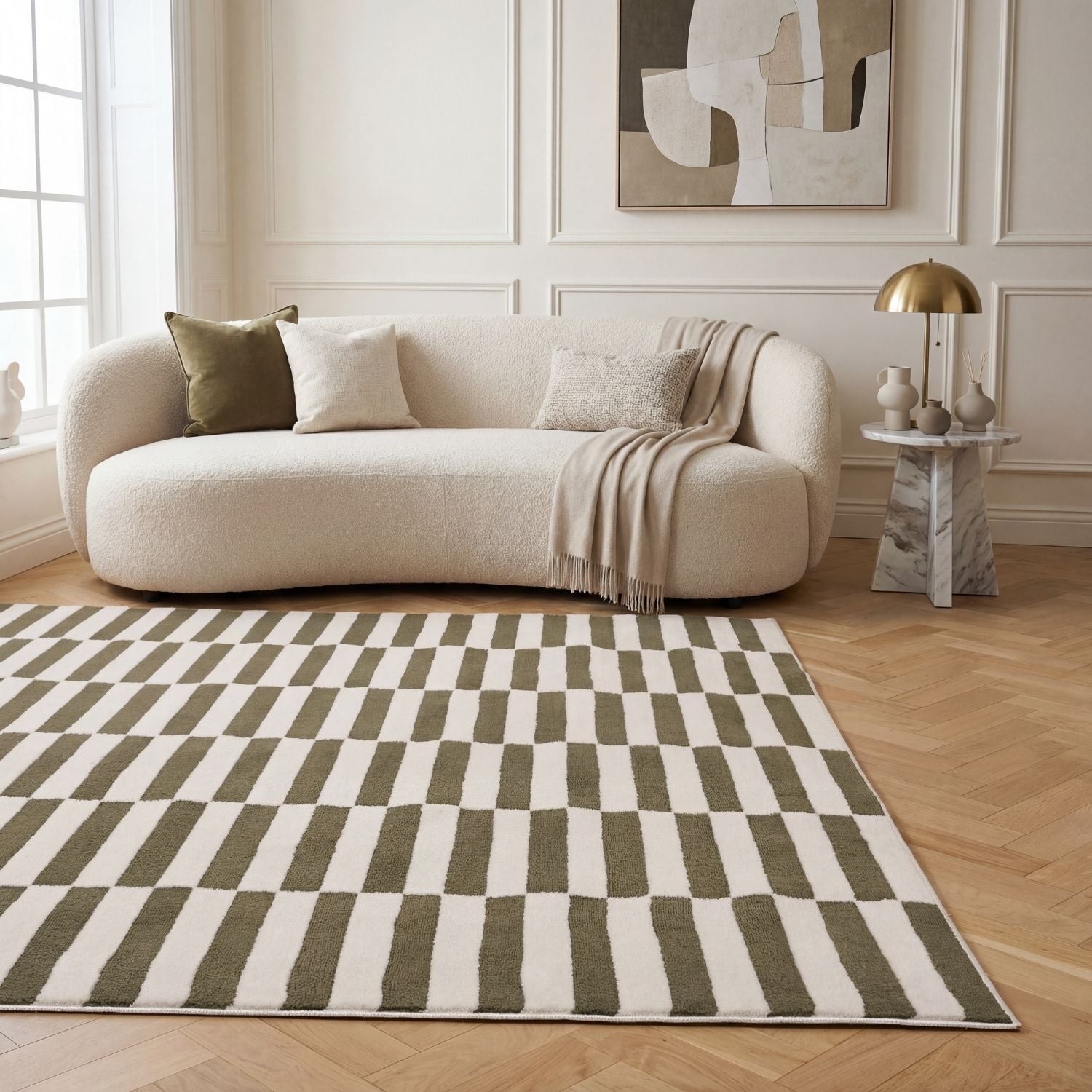 Beige sofa with decorative pillows and a blanket on a checkered green and white rug in a living room.