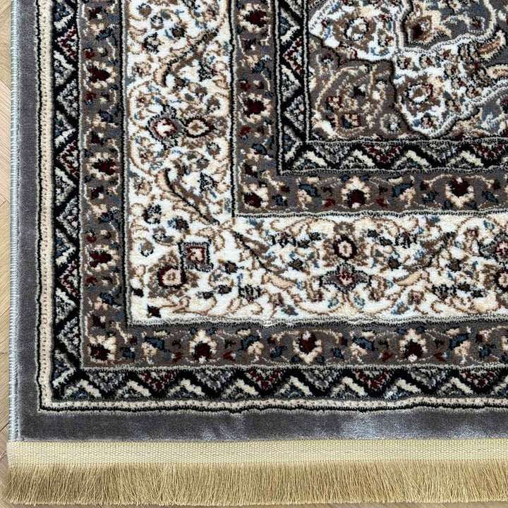 Close-up of a patterned rug with intricate designs and fringes.