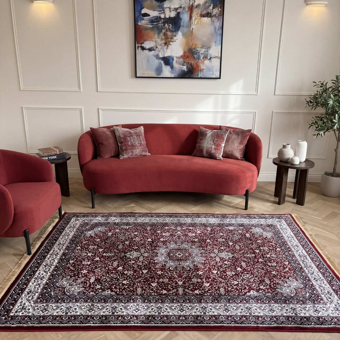 Living room with a red sofa, armchair, and patterned rug.