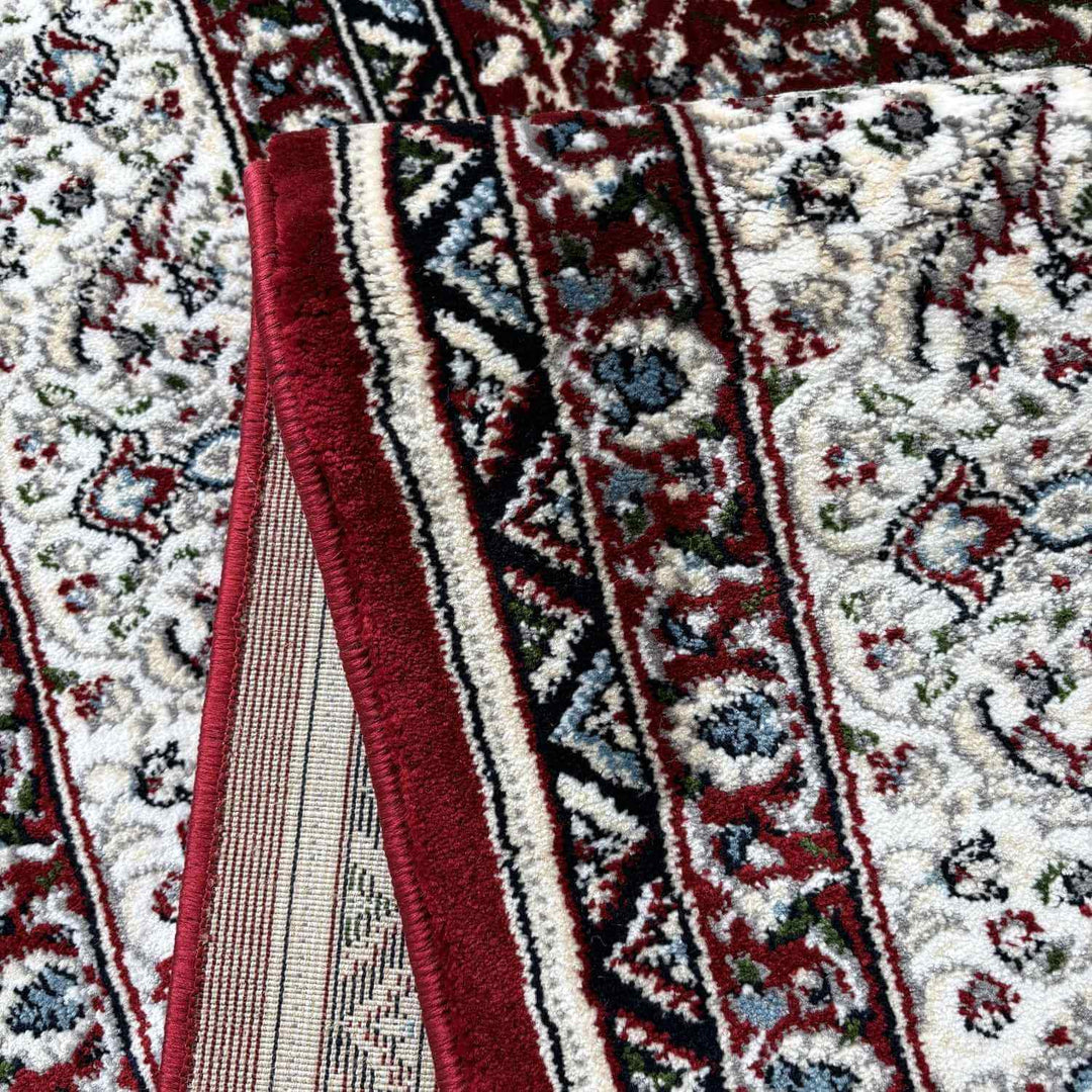 Close-up of a patterned rug with red, white, and black colors.