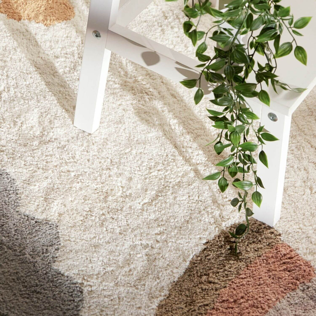 Close-up of a textured rug with a plant and chair leg.