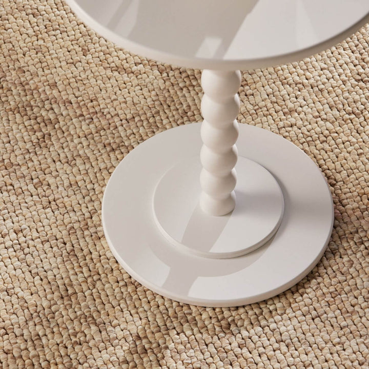White round table with a textured surface on a beige carpet