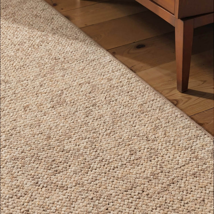 Beige carpet transitioned to wooden floor with a piece of furniture partially visible.