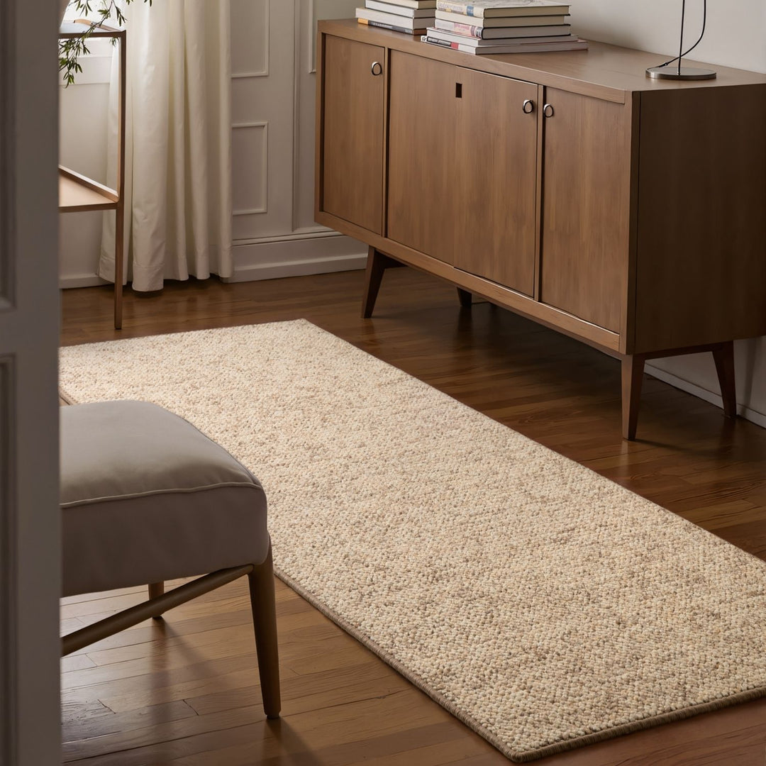 Beige rug on a wooden floor with a wooden sideboard and books in the background.