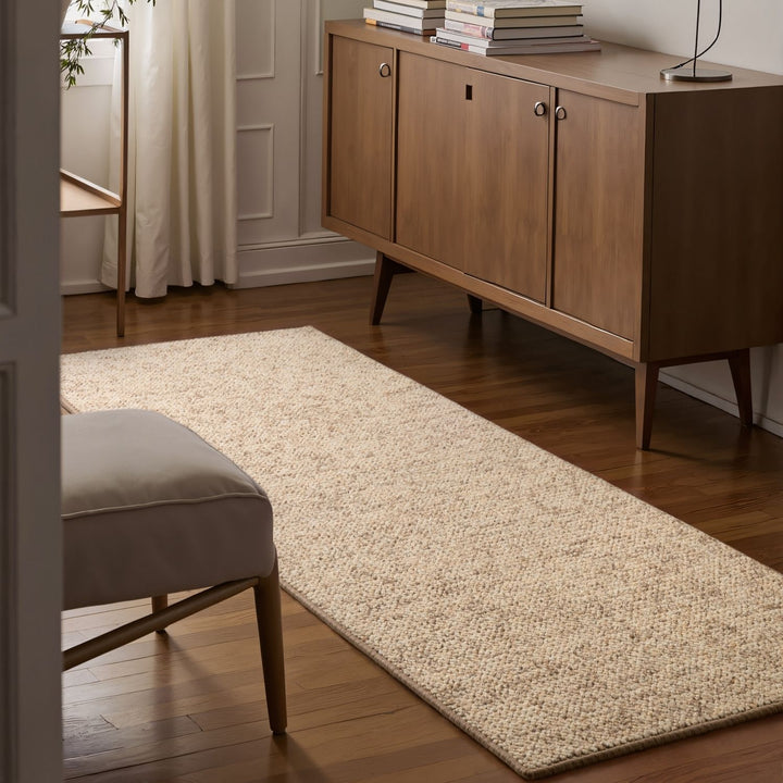 Beige rug on a wooden floor with a wooden sideboard and books in the background.