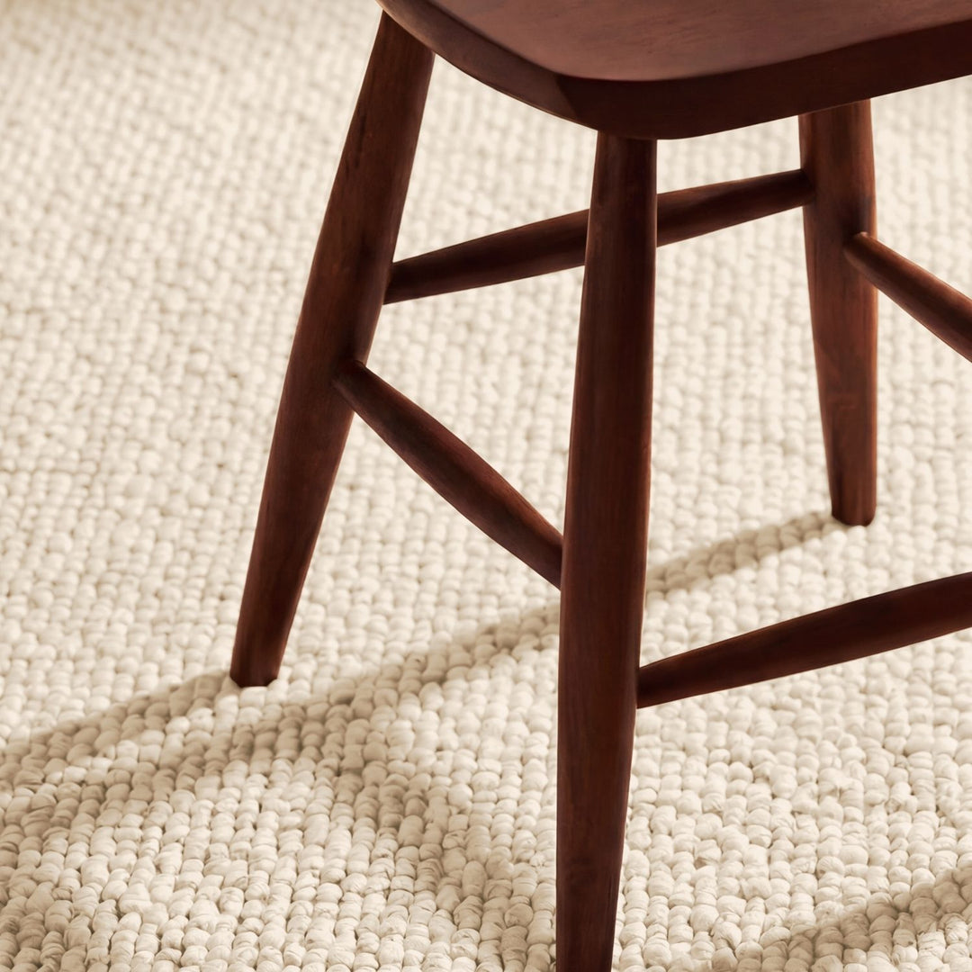 Wooden chair leg on a textured beige carpet