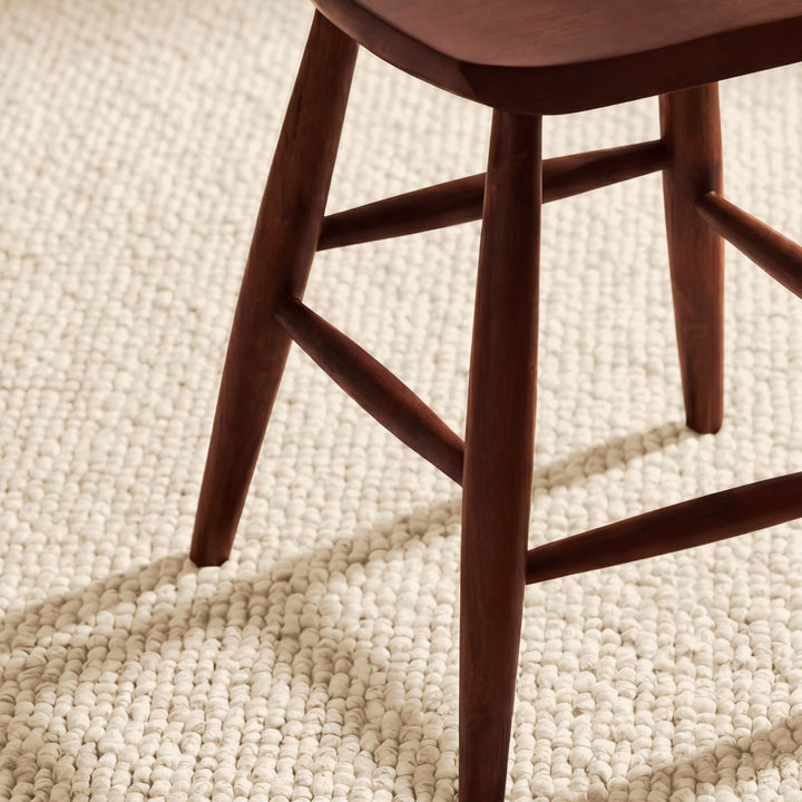 Wooden chair leg on a textured beige carpet