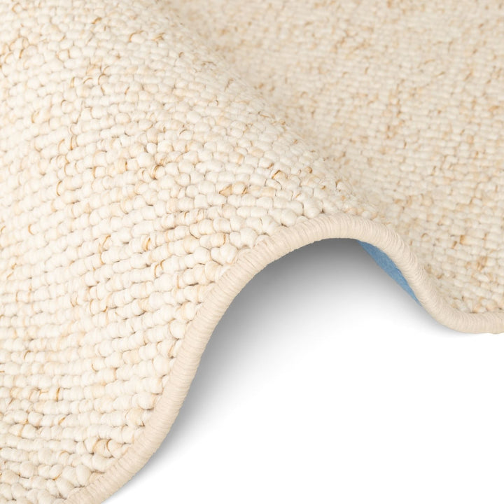 Close-up of a textured beige carpet corner on a white background