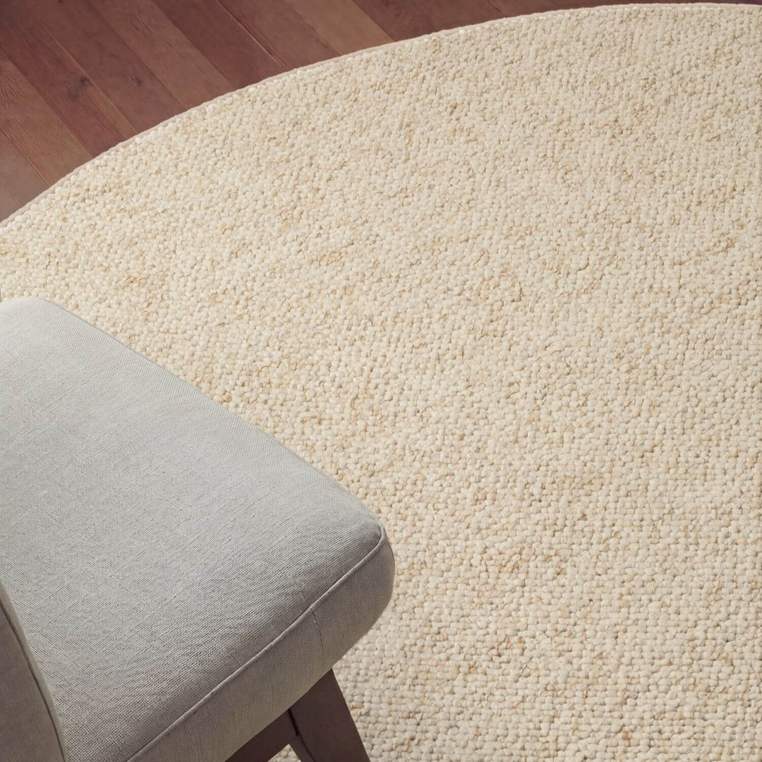 Beige textured rug with a gray cushion on a wooden floor