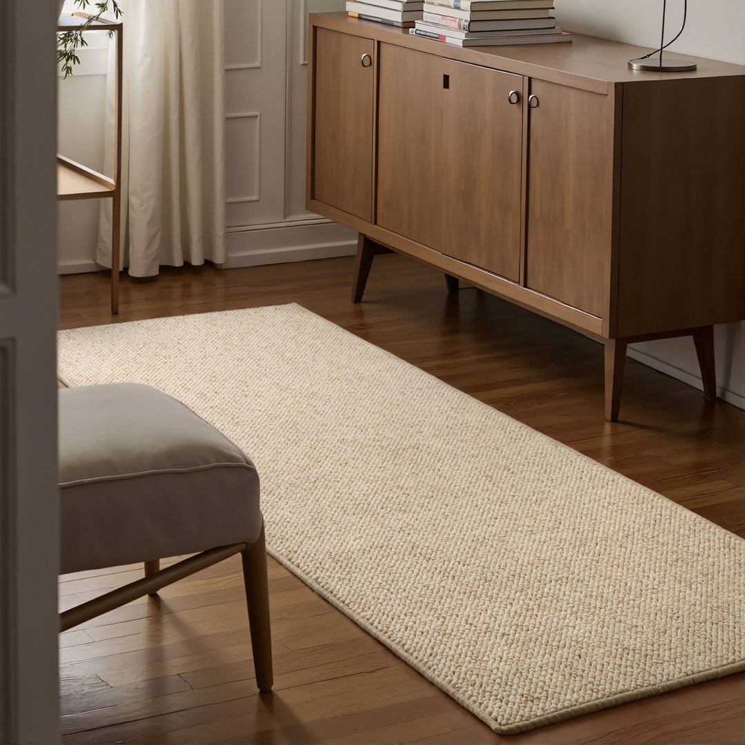 Beige rug on a wooden floor with a wooden sideboard and chair in a room.