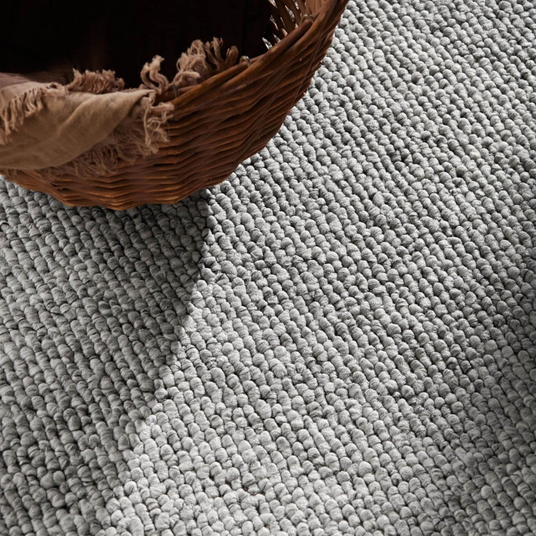 Textured gray rug with a woven basket on top
