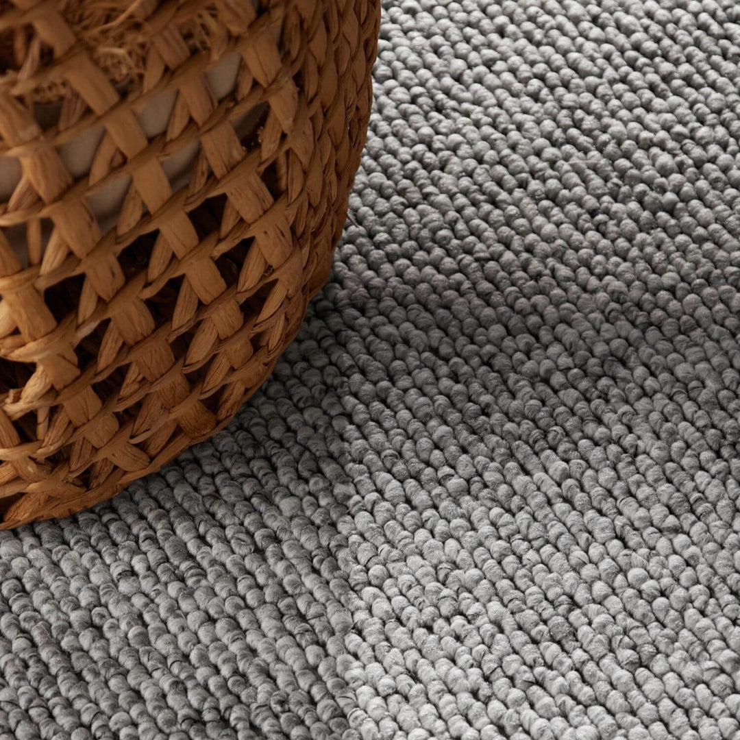 Gray textured carpet with a woven basket corner.