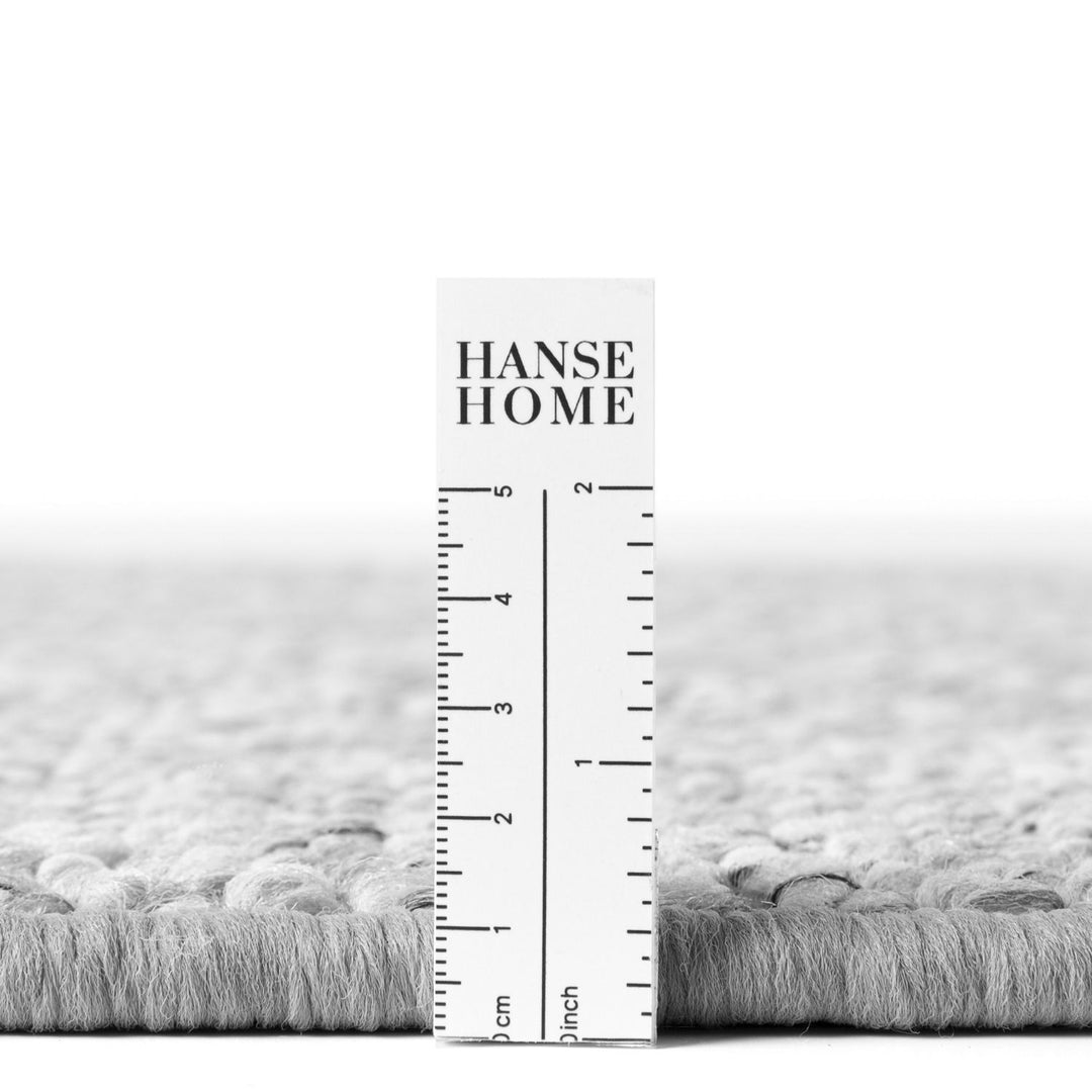 Gray textured rug with a ruler for scale and 'HANSE HOME' branding.